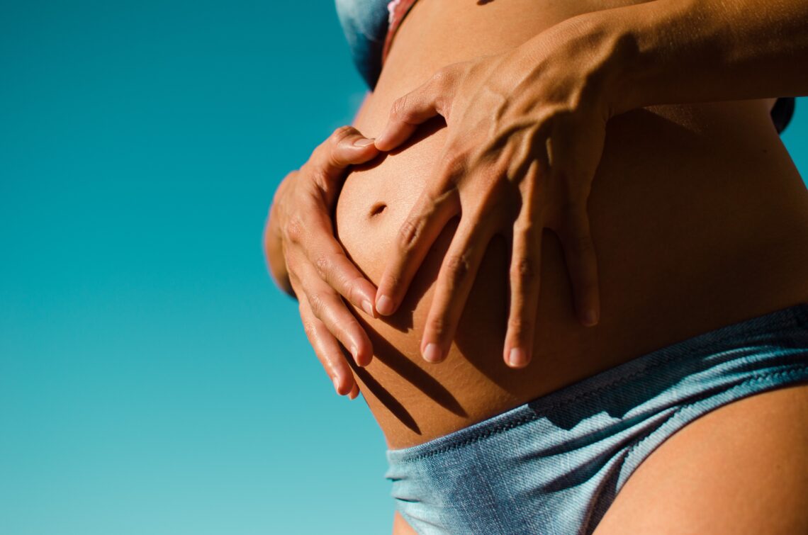 Pregnant woman making a heart with her hands over her stomach